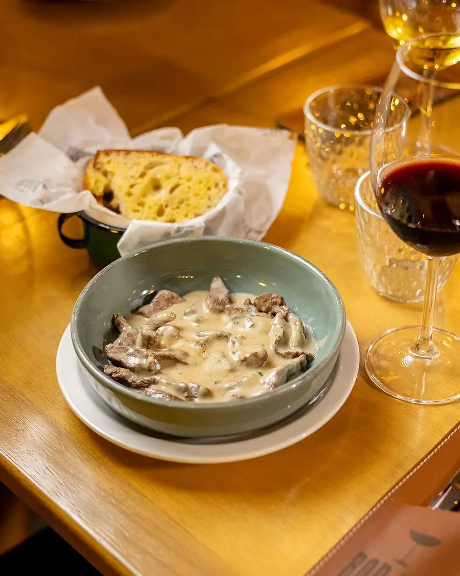 Mesa posta com prato, pão e taça de vinho tinto